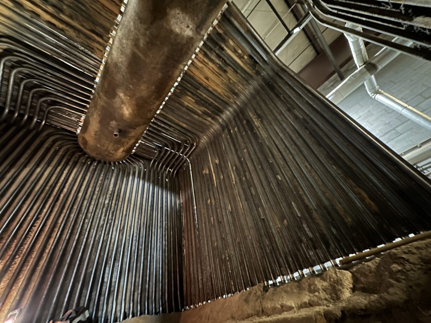 Welder installing and welding new watertube boiler tubes into steam drum during boiler retube project