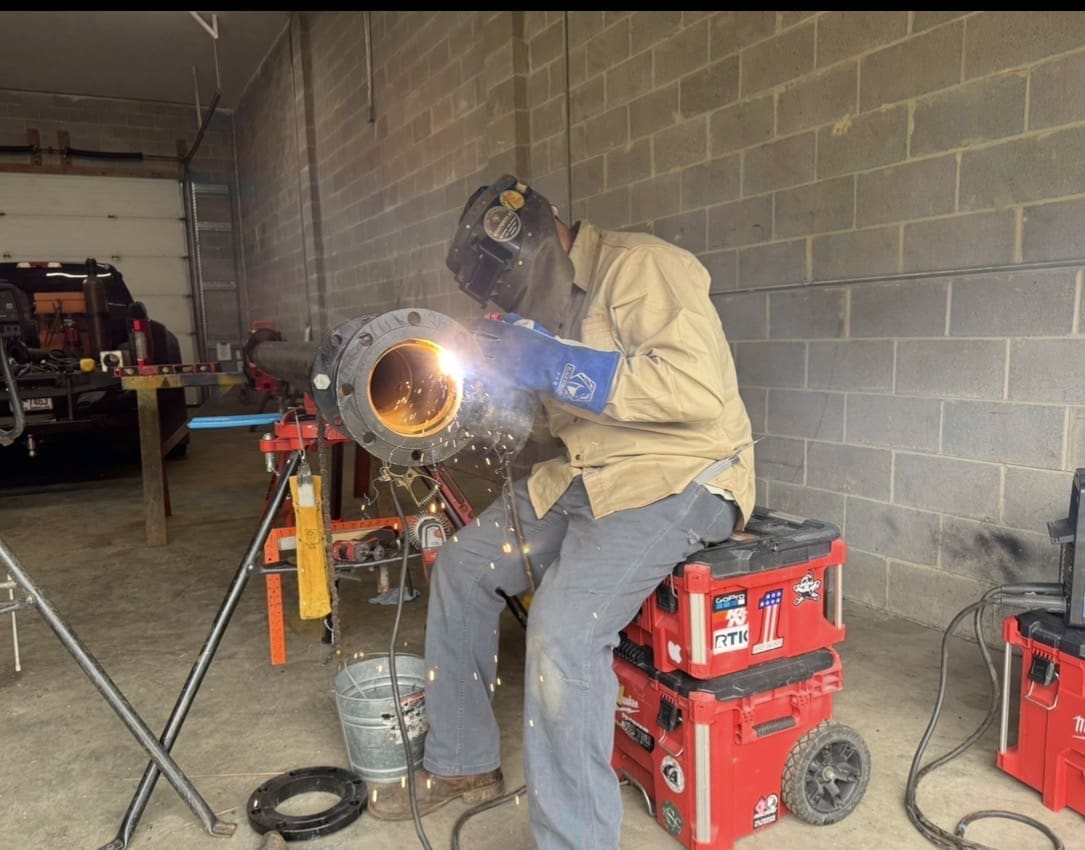 Welder prefabricating 6-inch chiller piping in fabrication shop for commercial mechanical system installation